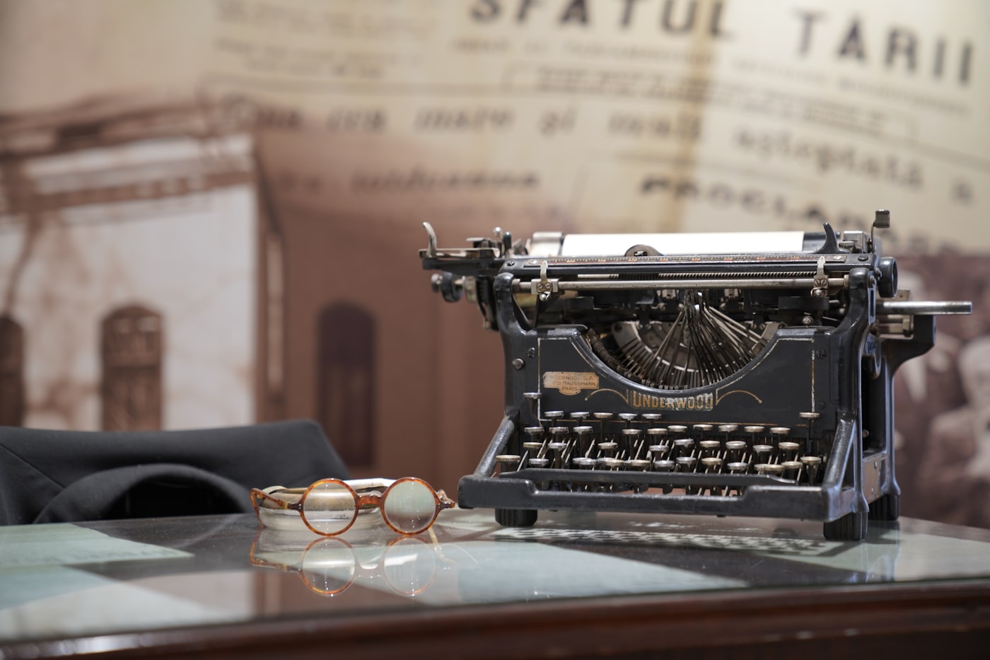 A vintage typewriter and glasses resting on a desk, evoking the craft of storytelling